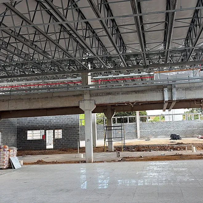 Interior da obra com a cobertura em treliça metálica montada